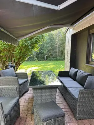an outdoor patio with wicker chairs and a table at Felicita in Jalhay