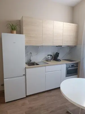 a kitchen with white cabinets and a sink and a table at AppartCosy in Liège
