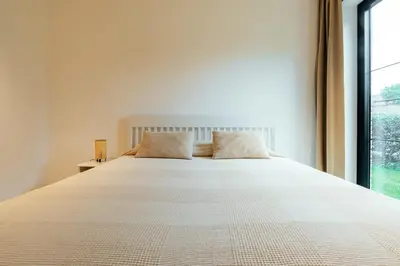 a white bed with two pillows in a room with a window at Bocca in Hasselt