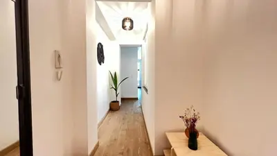 a hallway with white walls and a table with flowers at 301 Loft Chic Central in Liège