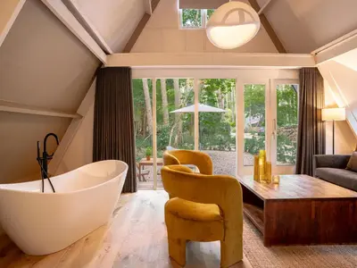 a bathroom with a tub and a table and chairs at Boshuisje Rekem - Plum in Lanaken