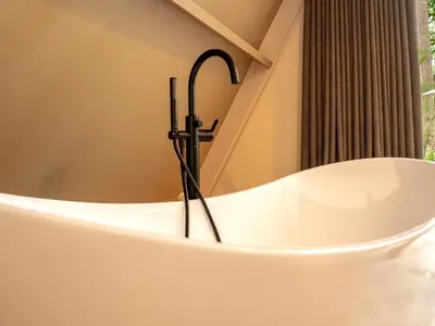 a bath tub with a black stick in it at Boshuisje Rekem - Plum in Lanaken