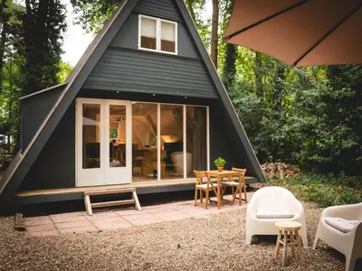 a black house with a pitched roof with a table and chairs at Boshuisje Rekem - Plum in Lanaken