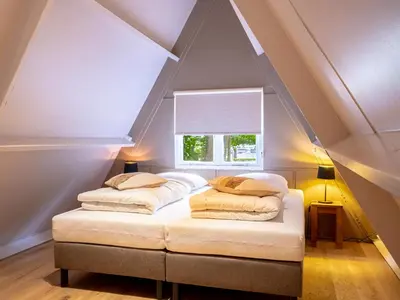 two beds in a attic bedroom with a window at Boshuisje Rekem - Plum in Lanaken