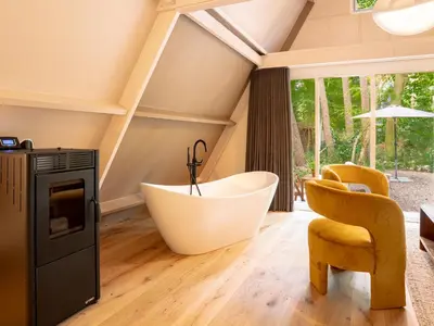 an attic bathroom with a tub and a chair at Boshuisje Rekem - Plum in Lanaken