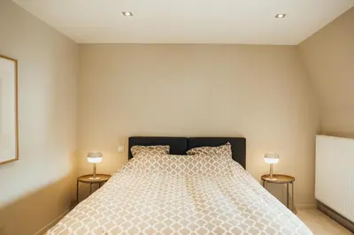 a bedroom with a large bed with two lamps at Liège Carré by WelcHome in Liège