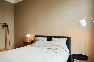 a bedroom with a bed with white sheets and a lamp at Liège Carré by WelcHome in Liège