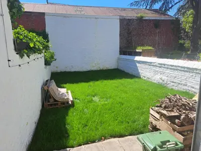 a yard with a white wall and green grass at Chambre luxe in Liège