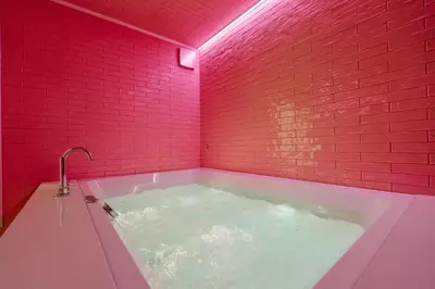 a bathroom with a hot tub with a red brick wall at Designer Hôtel in Heusy