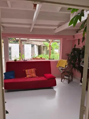 a red couch in a room with a window at De roze kamer in Mol