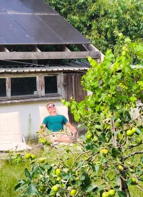a man sitting in a chair in front of a house at De roze kamer in Mol