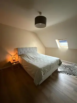 a bedroom with a white bed and a lamp at Duplex appartement met 3 slaapkamers in Genk