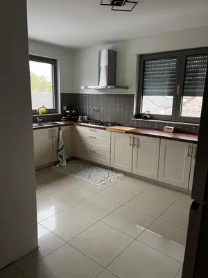 a kitchen with white cabinets and a tile floor at Duplex appartement met 3 slaapkamers in Genk