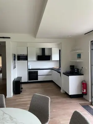 a kitchen with white cabinets and a table and chairs at Villa Weidezicht in Heusden - Zolder