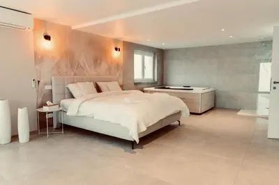 a bedroom with a large bed and a bath room at La Suite Kalys in Thimister