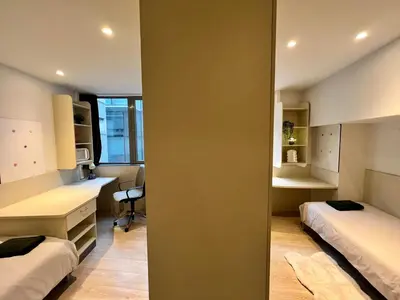 a room with two beds and a desk and a chair at Business trip - Sauna, gym, rooftop in Liège