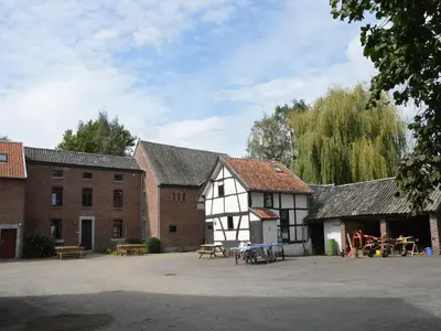a group of buildings with tables and benches in a courtyard at Farm Stay with Sauna, Teuven in Teuven