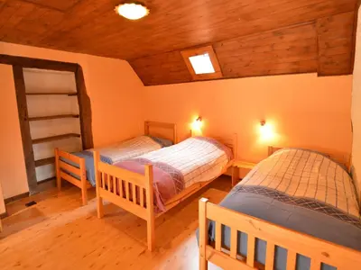 two beds in a room with wooden floors and wooden ceilings at Farm Stay with Sauna, Teuven in Teuven