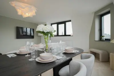 a dining room table with a vase of flowers and chairs at Superbe appartement 2 chambres en centre-ville in Liège