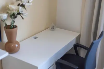 a white desk with a vase of flowers and a chair at Chambre de luxe RIO a Liège Sale de bain privée check in autonome cuisine partagée in Liège