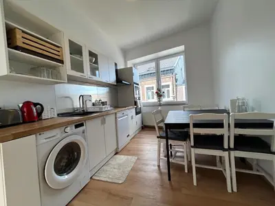 a kitchen with a washing machine and a table with chairs at Chambre de luxe Tokyo a Liège Sale de bain privée check in autonome cuisine partagée in Liège