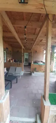an outdoor patio with a wooden roof with a bench at Gîte 