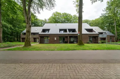 a brick house with trees in front of it at vakantie-hengelhoef in Houthalen-Helchteren