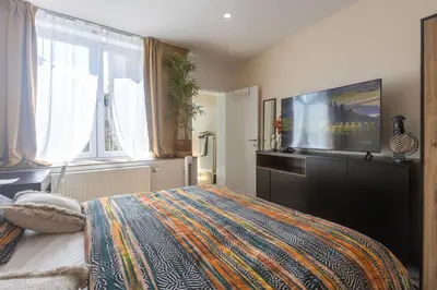a bedroom with a bed and a flat screen tv at Chambre de luxe Afrik a Liège Grande Sale de bain privée check in autonome cuisine partagée in Liège