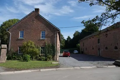 a red car parked in front of a brick building at Le Grand Jardin in Dalhem