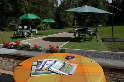 a table with magazines and umbrellas in a park at Le Grand Jardin in Dalhem