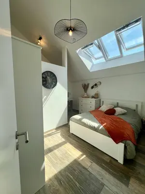 a bedroom with a bed with a clock and a skylight at La maison de MiLy in Bassenge
