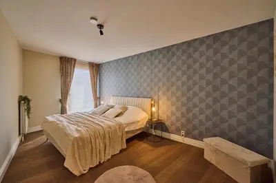 a bedroom with a bed and a table and a window at Aurora City Apartment in Lommel