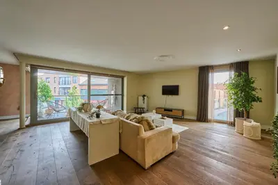 a large living room with a couch and a tv at Aurora City Apartment in Lommel