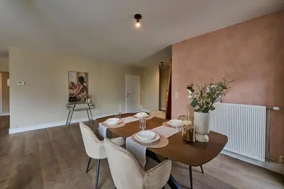 a dining room with a wooden table and chairs at Aurora City Apartment in Lommel