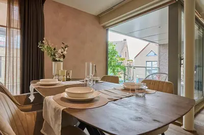 a dining room with a wooden table and a large window at Aurora City Apartment in Lommel