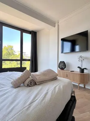 a bedroom with a white bed with a large window at Cozy and fully equipped in the center of Liege 4 guests in Liège