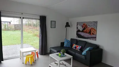 a living room with a black couch and a window at Camping Natuurlijk Limburg - Chalet 4 in Voeren