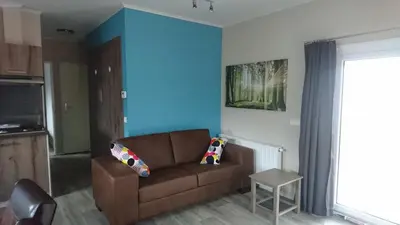 a living room with a brown couch and a blue wall at Camping Natuurlijk Limburg - Chalet 4 in Voeren