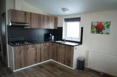 a kitchen with wooden cabinets and a sink and a window at Chalet - Camping Natuurlijk Limburg in Voeren