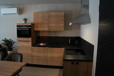 a kitchen with wooden cabinets and a black counter top at Camping Natuurlijk Limburg - Appartement in Voeren