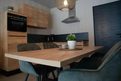 a wooden table in a kitchen with chairs and a potted plant at Camping Natuurlijk Limburg - Appartement in Voeren
