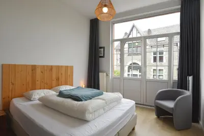 a bedroom with a bed with a chair and a window at La petite Naimette in Liège