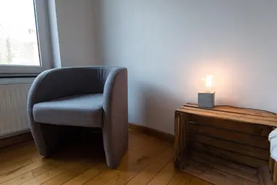 a chair sitting next to a table with a candle at La petite Naimette in Liège