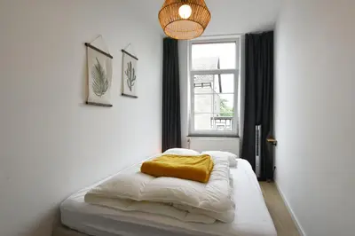 a bedroom with a bed with a yellow blanket on it at La petite Naimette in Liège