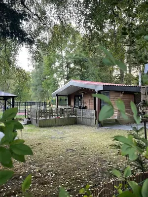 a building with a fence in a yard with trees at La Luna in Lanaken