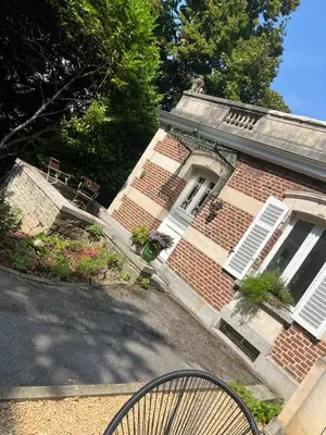 a brick house with white windows and a bike in front at Chez Léopold in Verviers