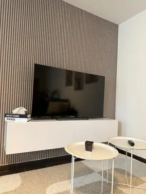 a living room with two tables and a large screen tv at Urban Cocoon in Liège