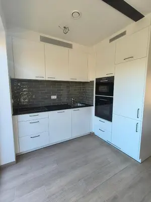 a kitchen with white cabinets and black appliances at Hof van Sassenbroek in Borgloon
