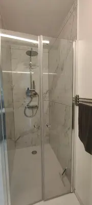 a shower with a glass door in a bathroom at Studio spacieux ,chaleureux et cosy in Heers
