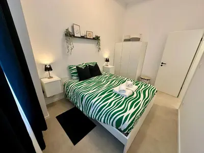 a small bedroom with a bed with a green and white comforter at L éclipse - Luxe moderniste en plein cœur de Liège in Liège